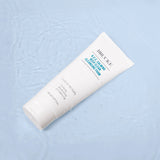 Cleansing foam tube with branding on a light blue textured background