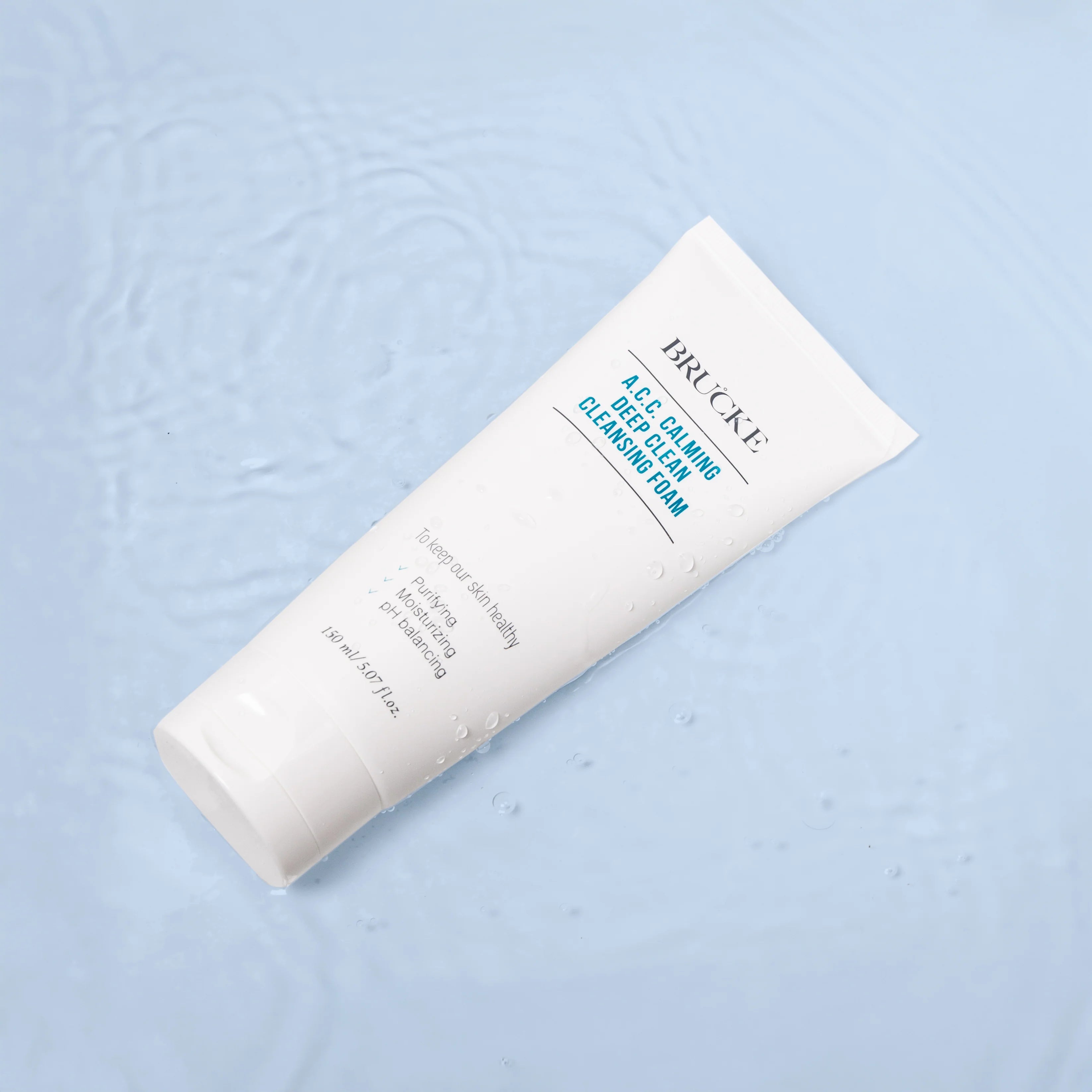 Cleansing foam tube with branding on a light blue textured background